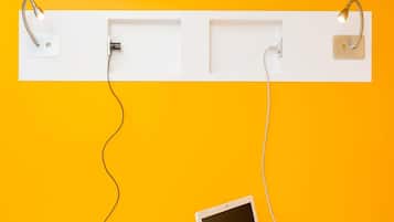 Una estantería blanca con dos lámparas de pared y una tableta sobre una pared amarilla.