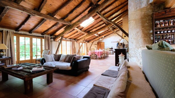 Un intérieur rustique en bois, avec un plafond haut, un canapé, une table et un coin repas.