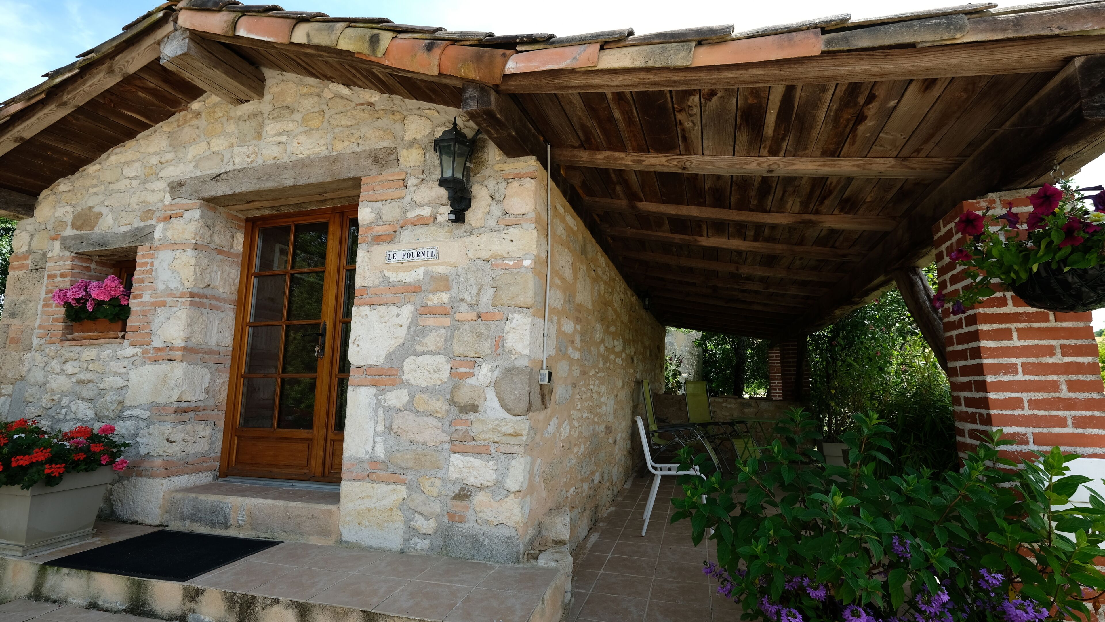 A stone building with a wooden door and a sign reading 'LE FOURNIL'.