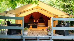 A tented accommodation with a wooden deck, wicker furniture, and a central bed area. - Domaine Les Miquels (Castelnau-de-Montmiral)