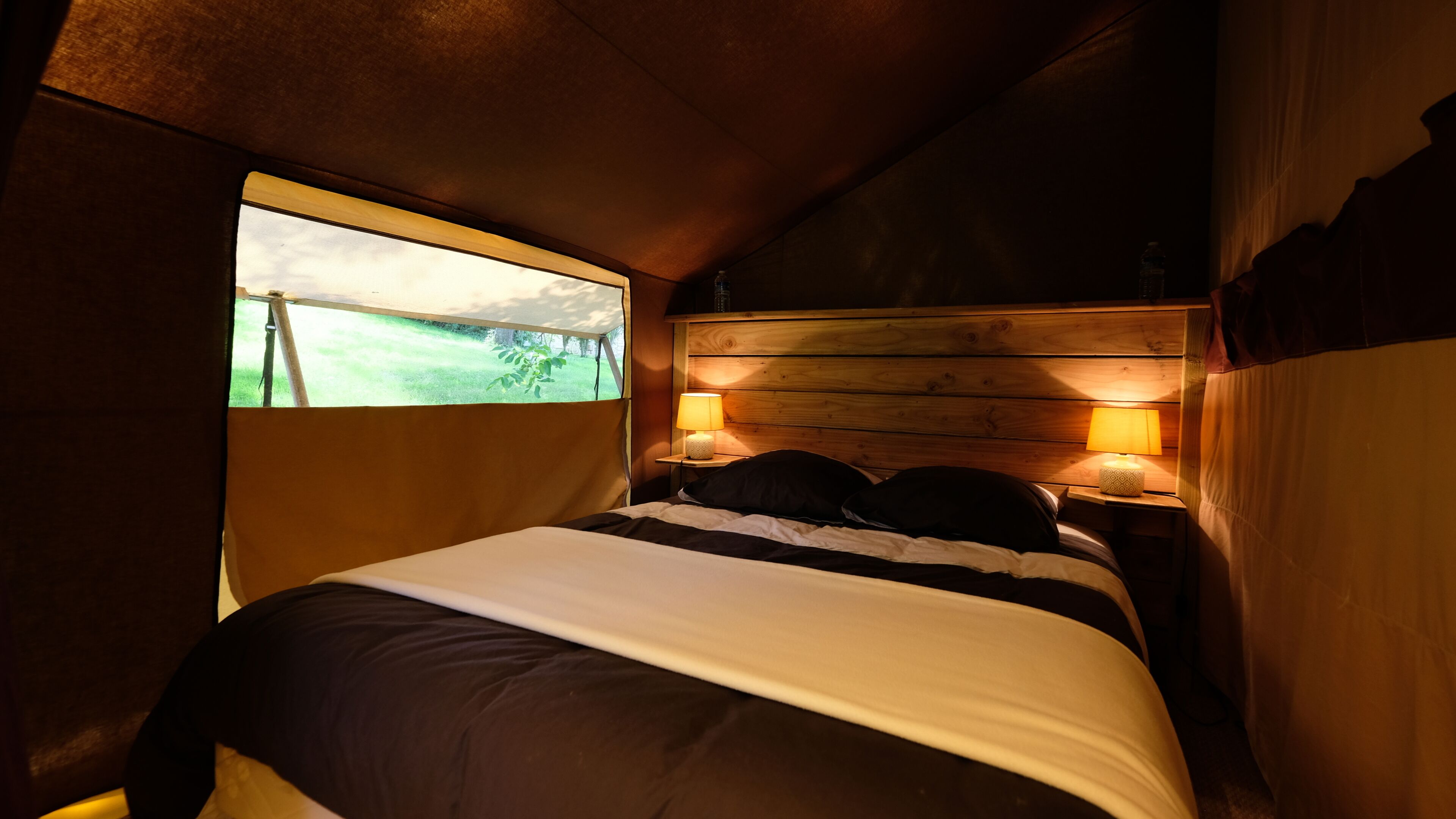 Une chambre à coucher avec un lit, deux lampes de chevet, une fenêtre et une tête de lit en bois.