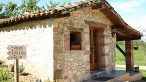Un bâtiment en pierre avec un toit en tuiles, une porte en bois et un panneau indiquant la direction de la réception, du réfectoire et de la piscine.