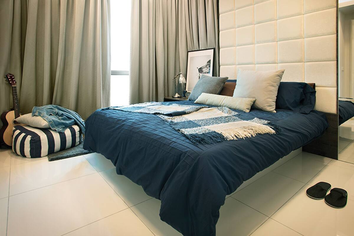 A bedroom with a bed, pillows, a guitar, and a bean bag chair.