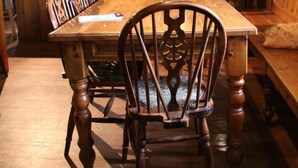 A wooden dining table with chairs, a bar area with shelves of bottles, and a wooden bench. - Holly Bush Inn (Hexham)