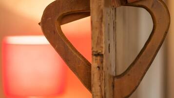 Ein Holzelement mit herzförmiger Aussparung, möglicherweise ein dekorativer Gegenstand oder ein Möbelteil, mit verschwommenem Hintergrund, der eine Lampe und ein kugelförmiges Objekt auf einer Oberfläche zeigt.