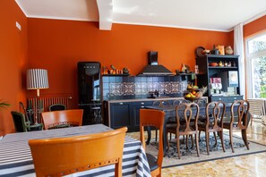 A kitchen with a dining area, featuring a striped tablecloth, wooden chairs, and a tiled backsplash.