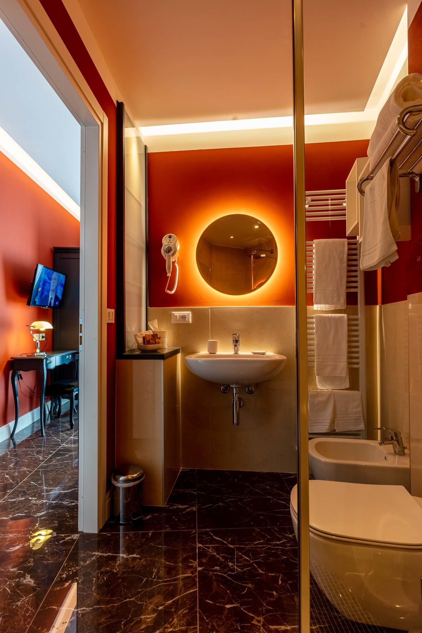 A modern bathroom with a marble floor, a large sink, a bathtub, and a mirror with a telephone.