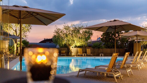 Zona junto a la piscina con sillones reclinables y sombrillas, una piscina y vistas del paisaje circundante.