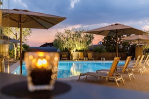 A poolside area with lounge chairs and umbrellas, a pool, and a view of the surrounding landscape. - Art Hotel Ventaglio (Bardolino)