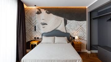 A modern bedroom with a large bed, a headboard, a nightstand, a lamp, and a wardrobe.