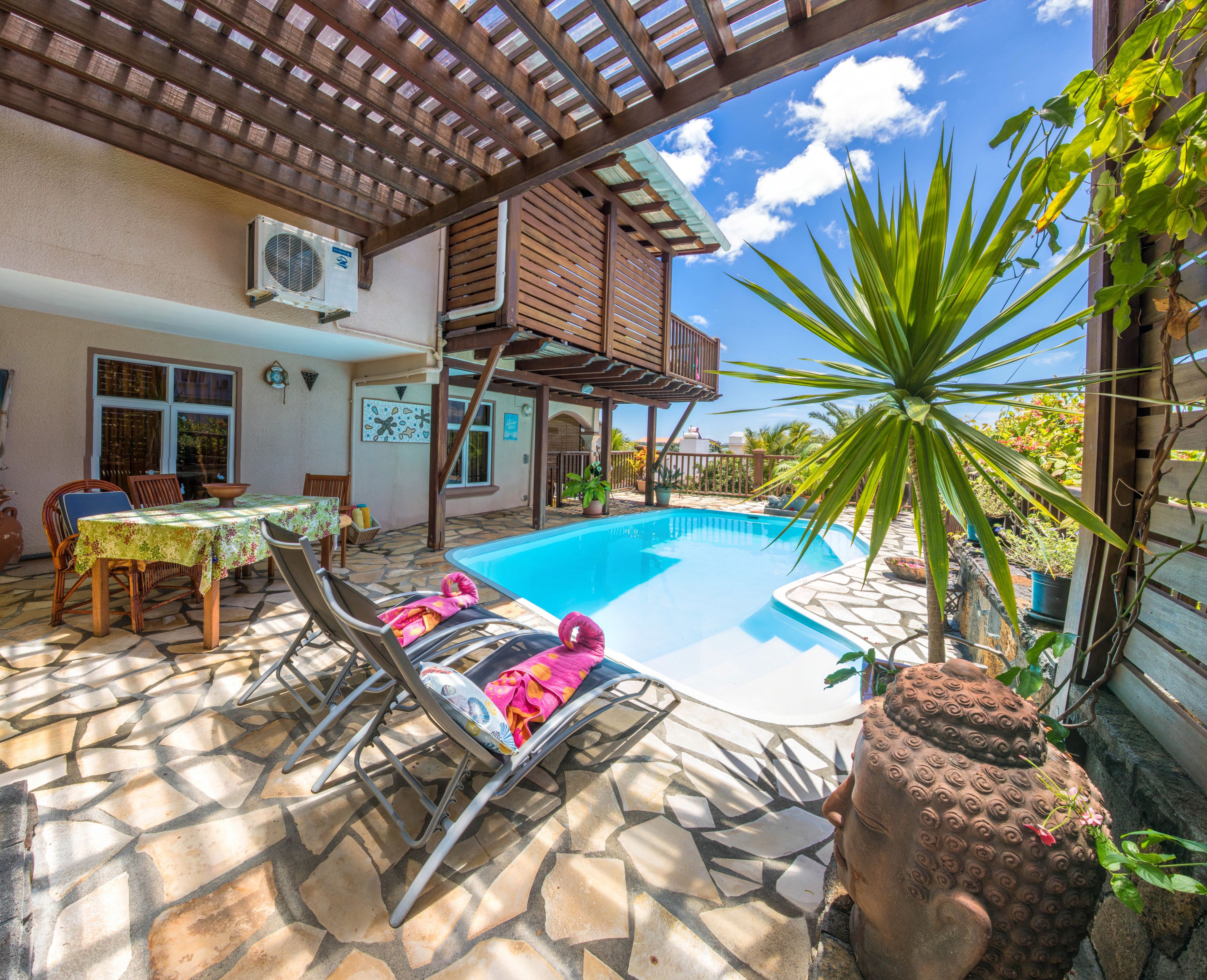 A pool area with lounge chairs, a table, and a pergola.
