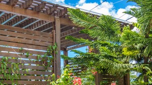 A wooden pergola with climbing plants and a potted tree. - Blue Lagoon Villa (La Gaulette)