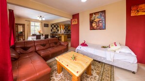 A living room with a brown leather sofa, a white sofa, a wooden coffee table, and a patterned rug. - Blue Lagoon Villa (La Gaulette)
