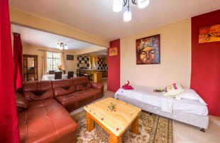 A living room with a brown leather sofa, a white sofa, a wooden coffee table, and a patterned rug.