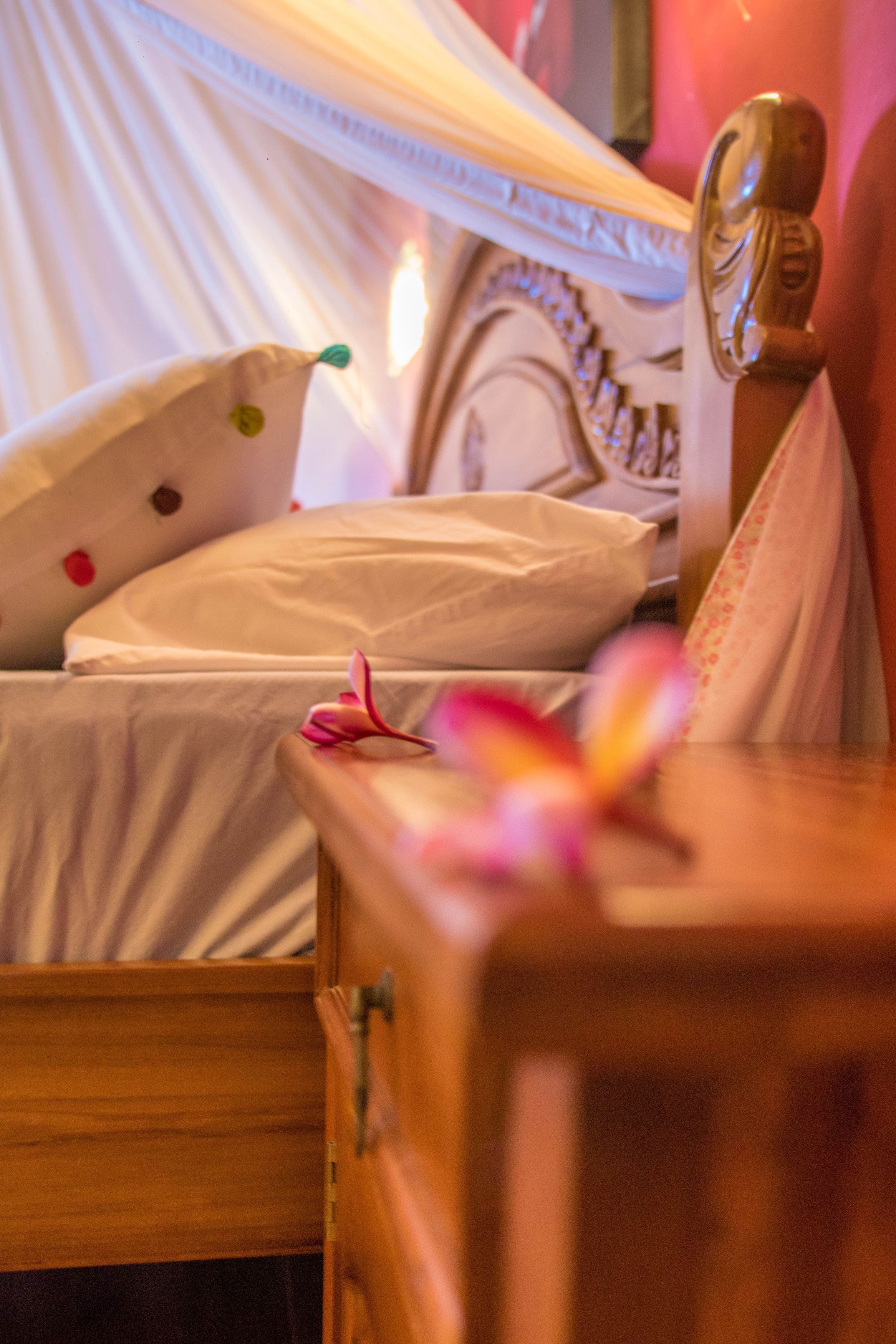 A bed with a canopy, a wooden nightstand, and a decorative headboard.