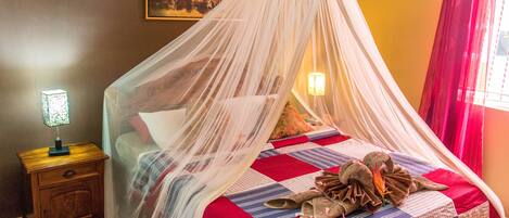 A bed with a canopy, a nightstand, a lamp, and a painting on the wall.