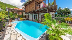 A two-story house with a swimming pool, surrounded by tropical plants and a stone pathway. - Blue Lagoon Villa (La Gaulette)