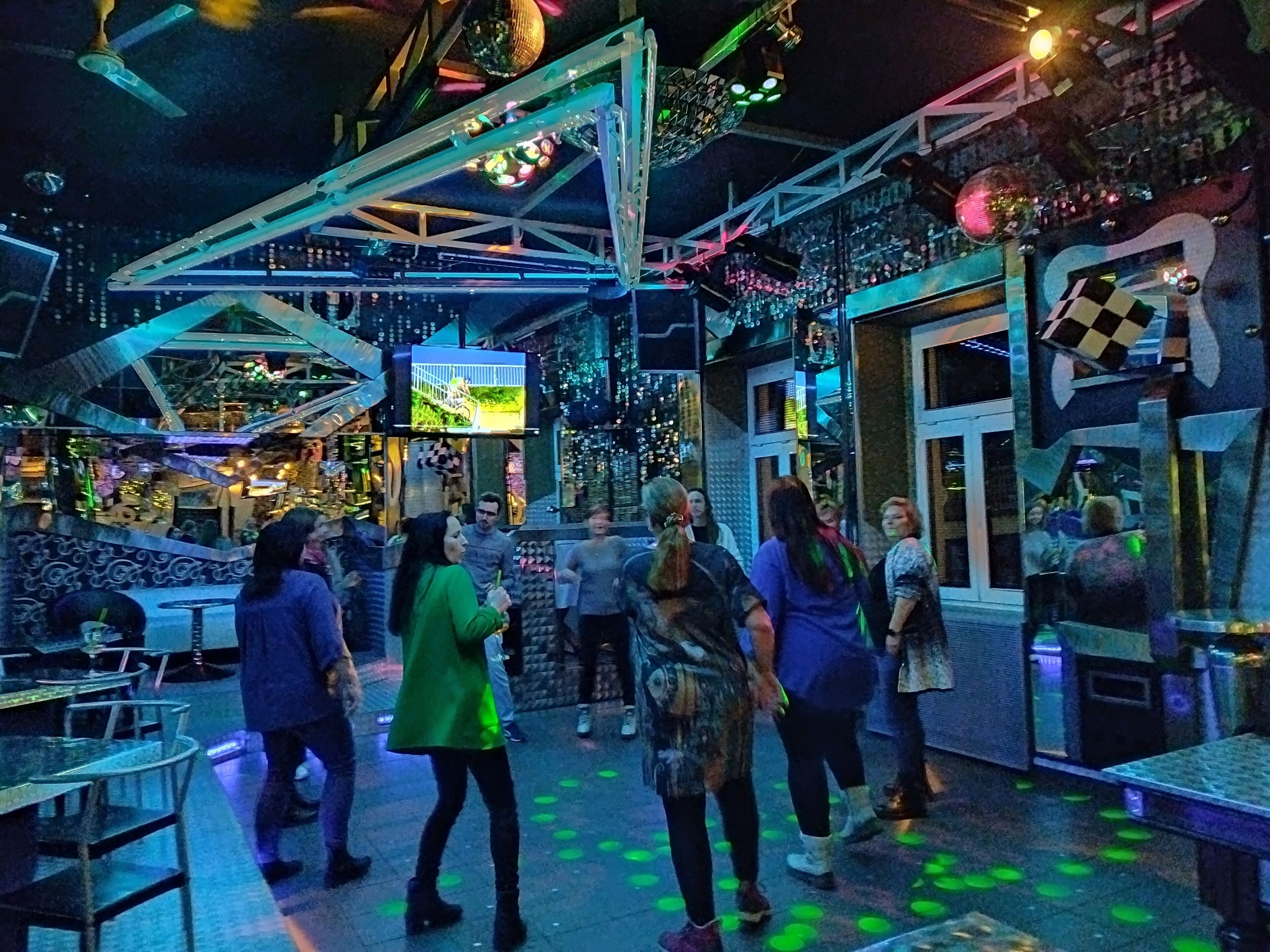 A modern indoor space with a high ceiling, geometric metal structures, and a disco ball.