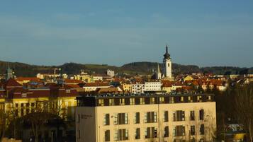 A town with a prominent church tower, a mix of residential and commercial buildings, and a flat terrain with hills in the background.