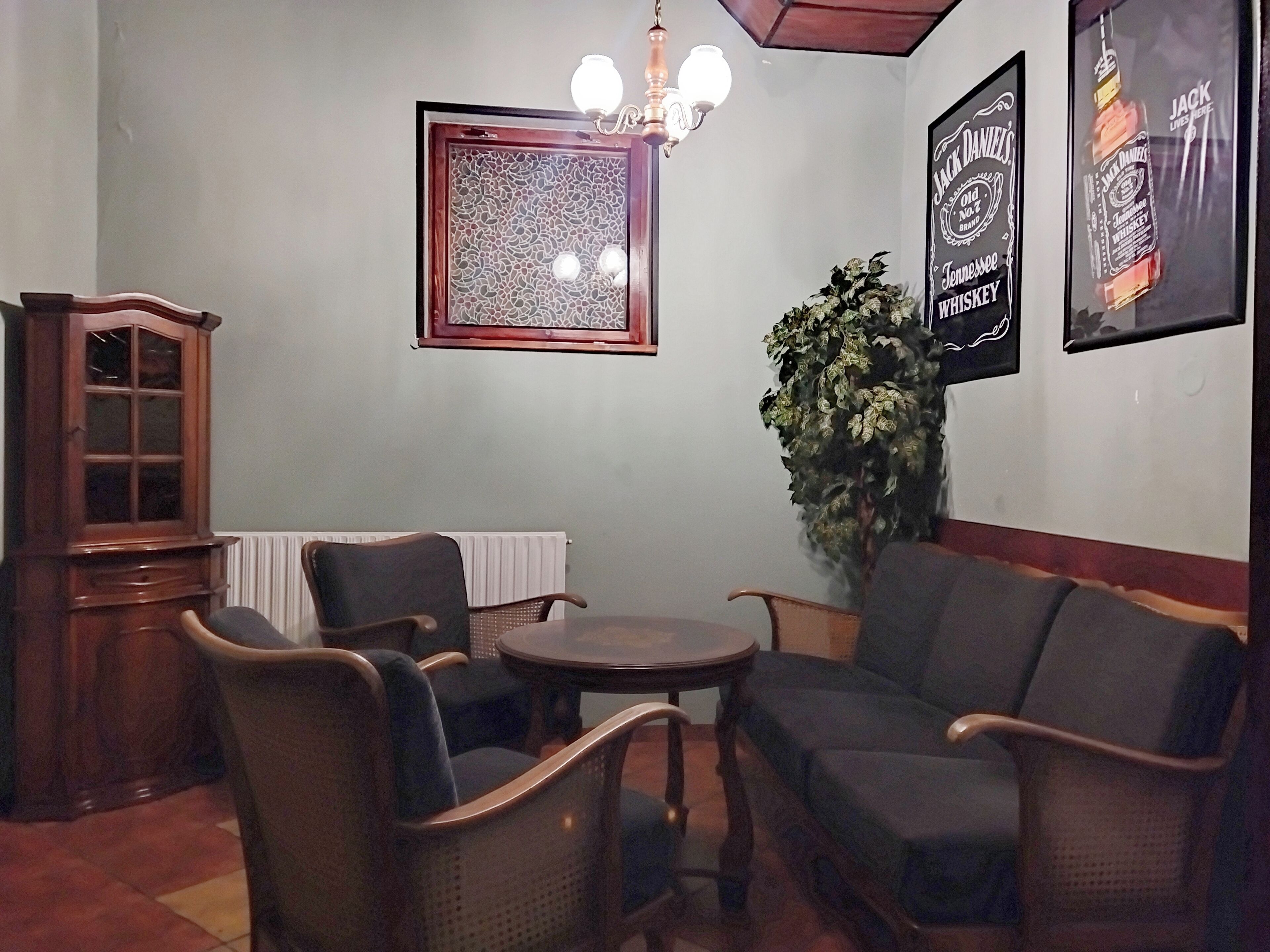 A room with a round table and four chairs, a cabinet, a potted plant, and two framed posters on the wall.