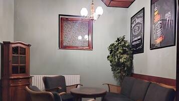 A room with a round table and four chairs, a cabinet, a potted plant, and two framed posters on the wall.