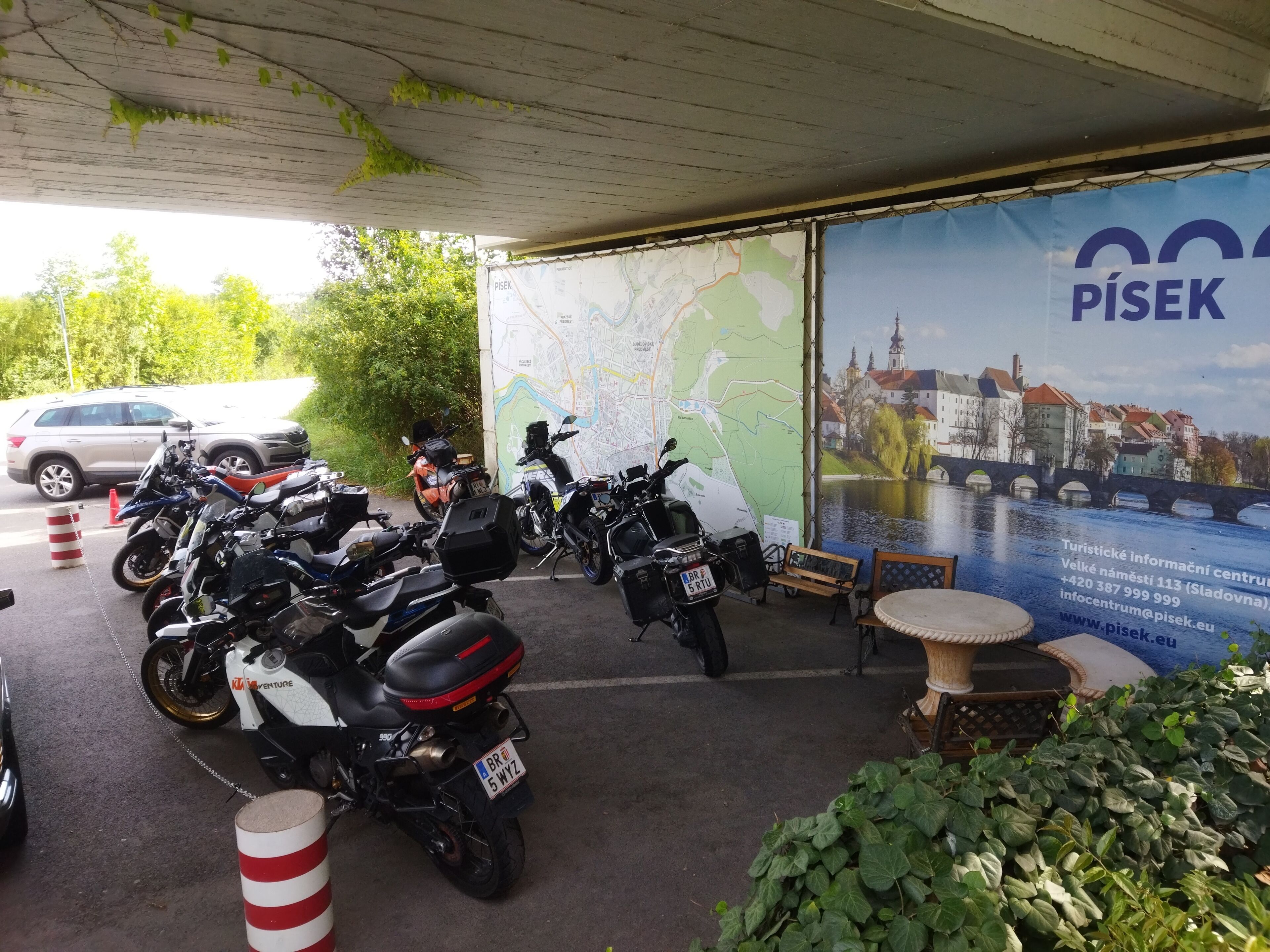 A covered parking area with motorcycles parked under a map and a large poster of a cityscape.