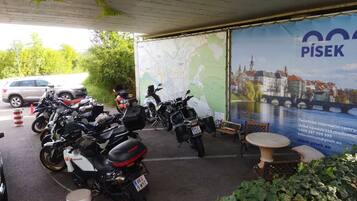 A covered parking area with motorcycles parked under a map and a large poster of a cityscape.
