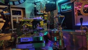 A bar area with a neon sign reading "Cafe Bar," a coffee machine, and a beer tap.