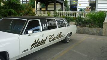 Een klassieke Cadillac auto geparkeerd voor een gebouw met een restaurant en een fontein.