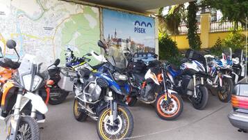 Motocicletas estacionadas em área coberta, com um mapa e uma placa ao fundo.