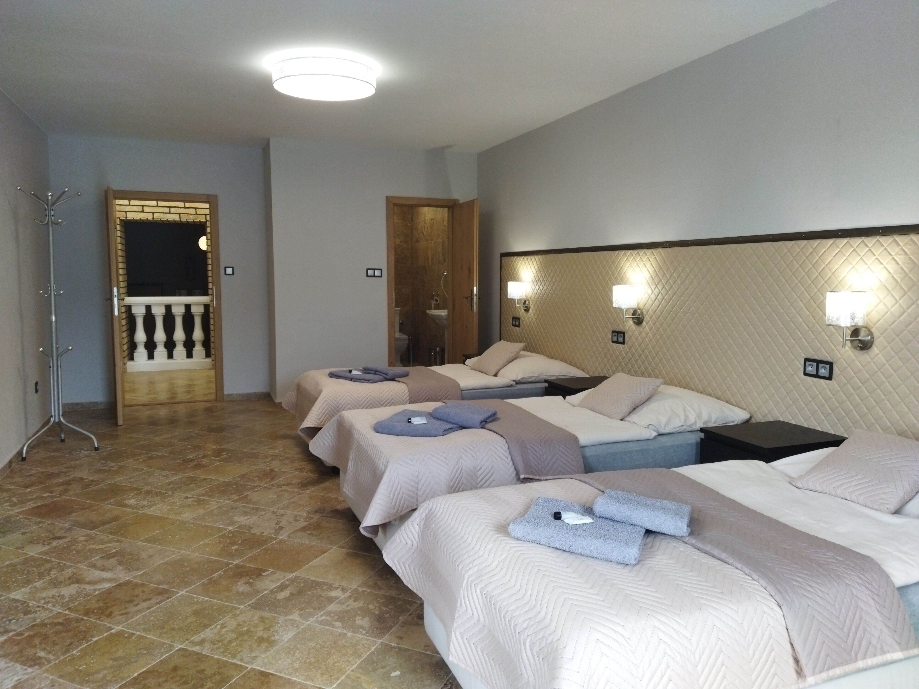 Habitación de hotel con tres camas, un baño y un balcón.