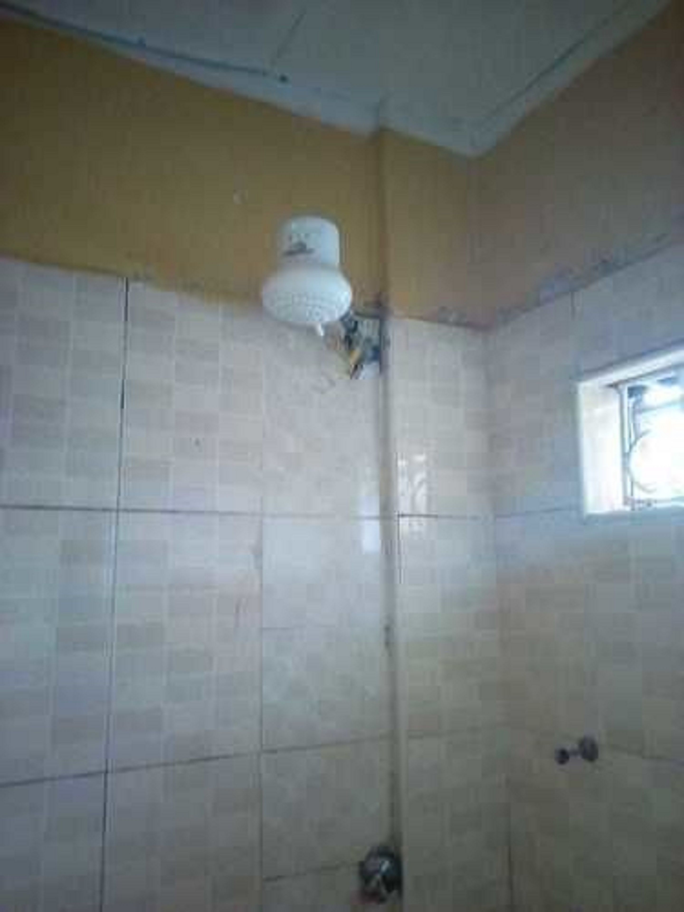 A bathroom with tiled walls, a window, and a shower area.