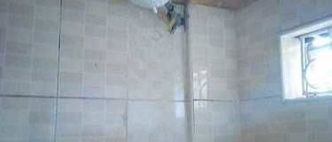 A bathroom with tiled walls, a window, and a shower area.