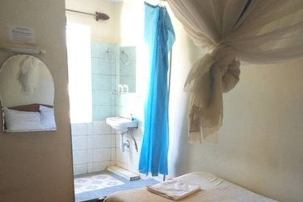 A bedroom with a bed, a bathroom with a shower, and a sink.