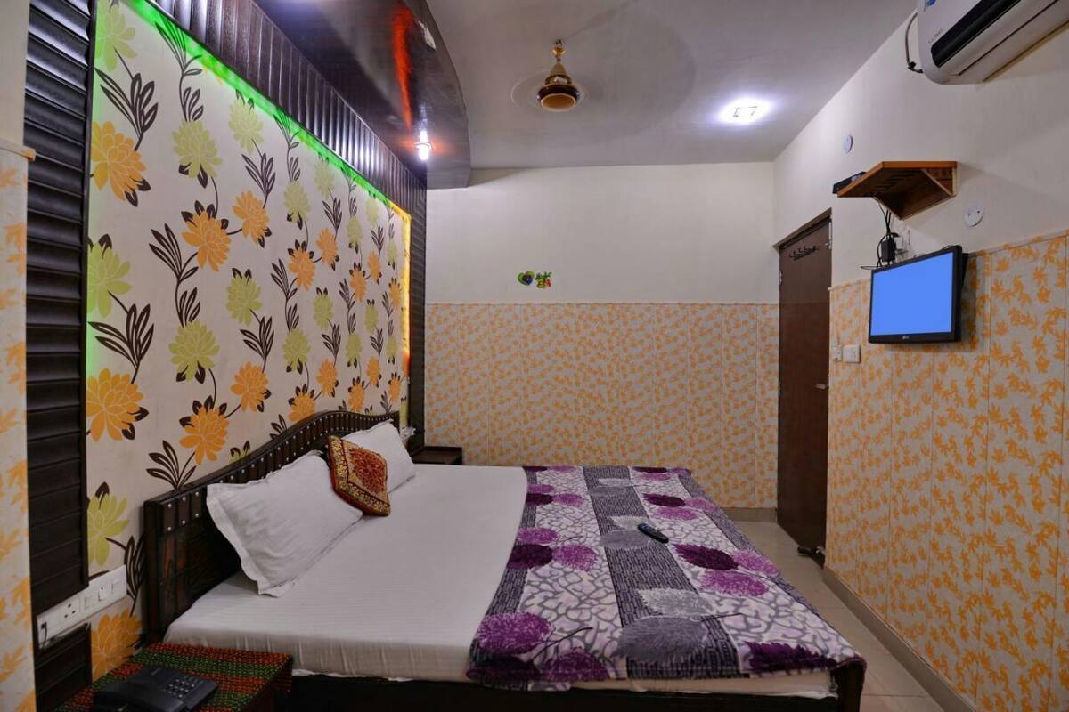 Un dormitorio con una cama, un televisor y una estantería en la pared.