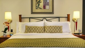 A neatly made bed with a green patterned bedspread, two pillows with a diamond pattern, and a framed artwork above the bed. - Hotel Dharam Villa (Kalka)