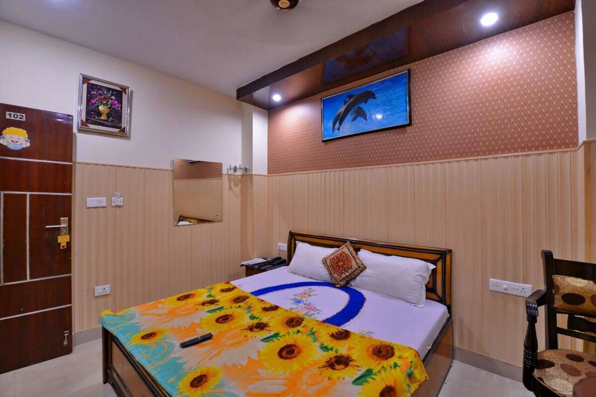 Habitación de hotel con cama, armario de madera, espejo, un cuadro colgado en la pared y un diseño decorativo en la pared.