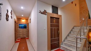 A hotel hallway with a wooden door marked '104', a staircase, and a welcome mat. - Hotel Dharam Villa (Kalka)