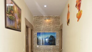 A hallway with a stone wall, a framed picture, and a red carpet. - Hotel Dharam Villa (Kalka)