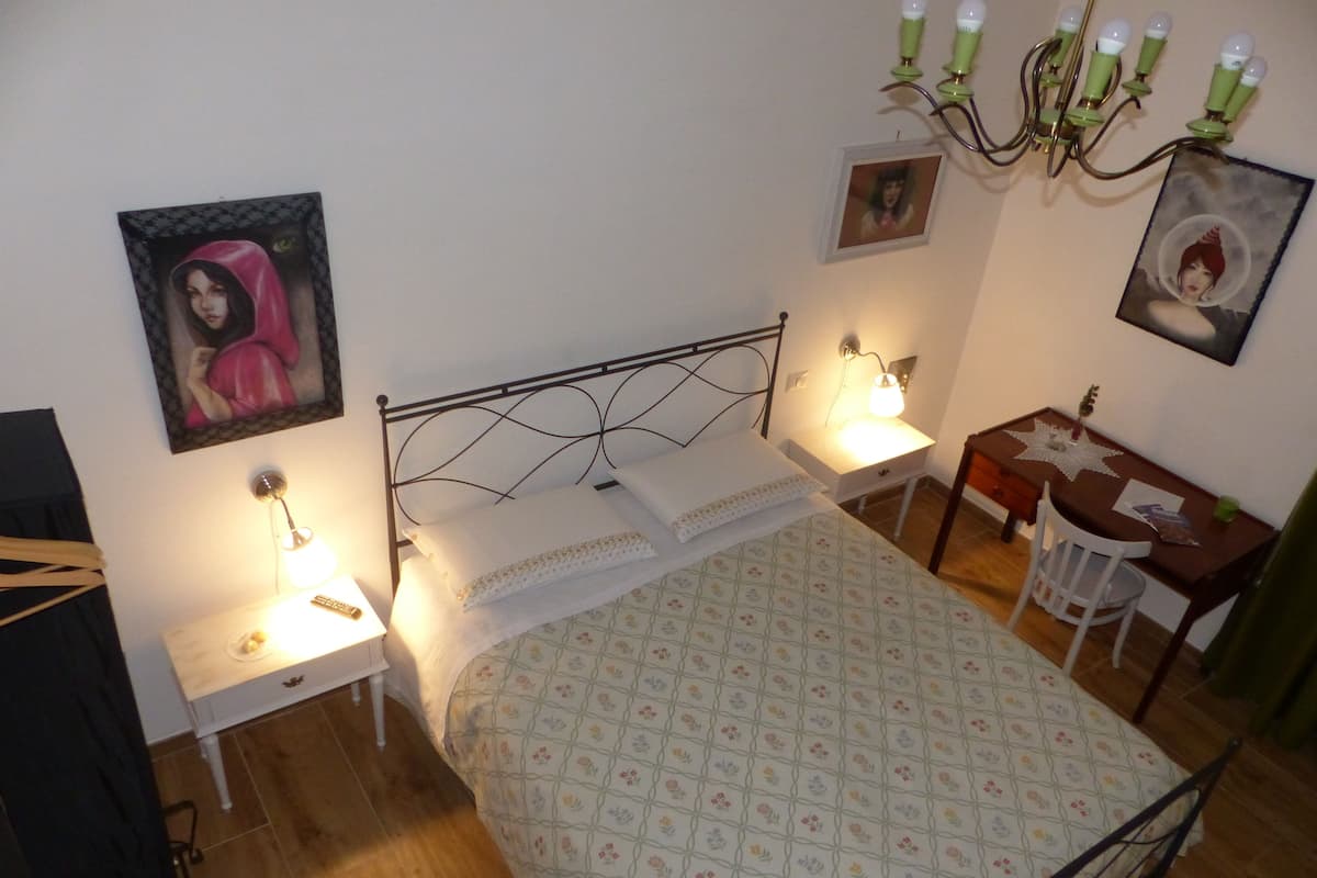 A bedroom with a bed, two bedside tables, a desk, and a chair.