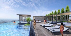 Una piscina infinita en la azotea con sillones de descanso y un área de estar techada.