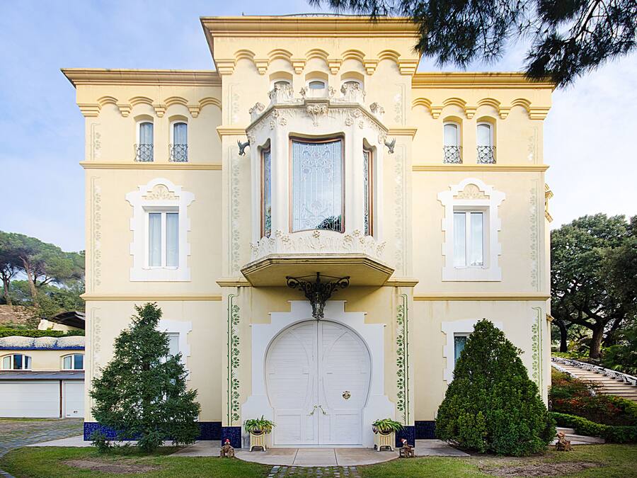 A two-story building with a symmetrical facade, large central doors, and decorative elements.