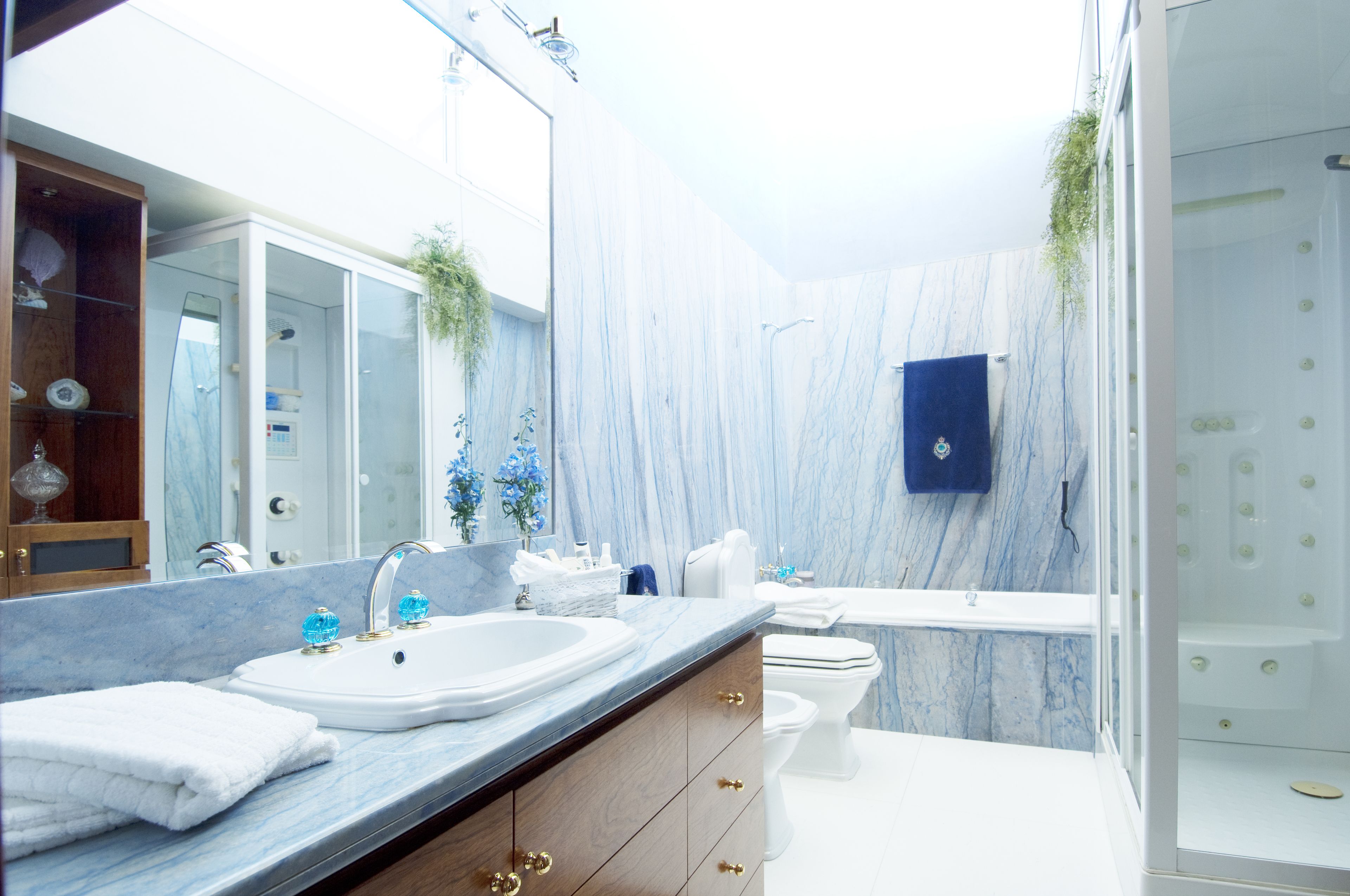 A modern bathroom with a marble vanity, a bathtub, and a glass-enclosed shower.