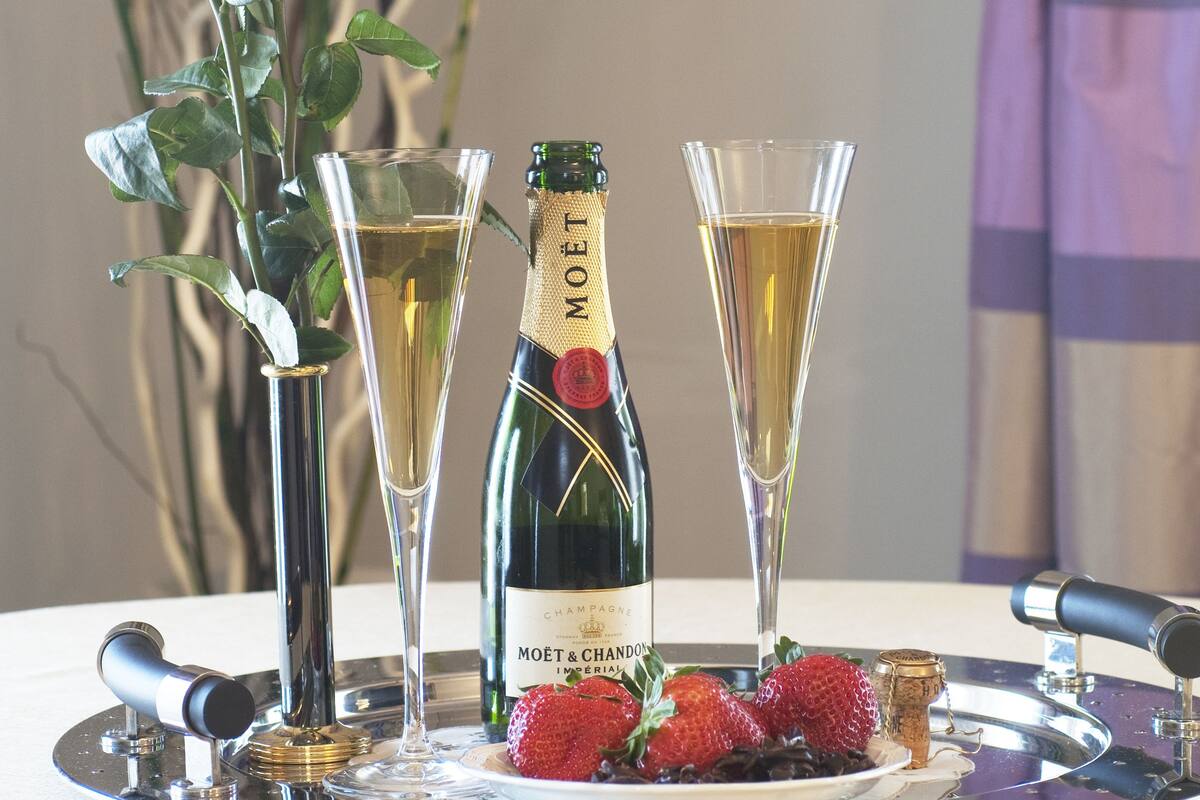 Une bouteille de champagne, deux verres et une assiette de fraises, le tout sur un plateau.