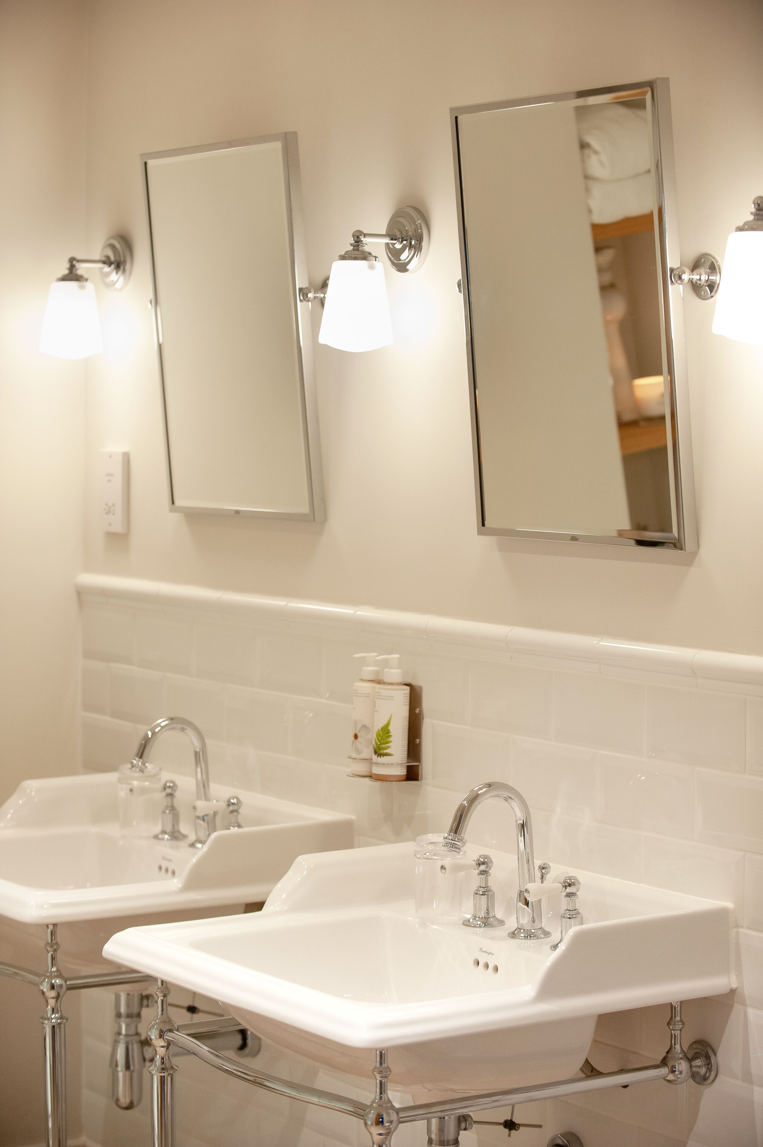 A bathroom with two sinks, a mirror, and wall-mounted lights.