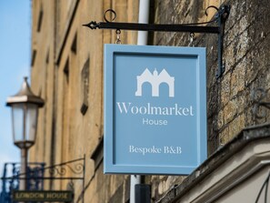 Une enseigne indiquant « Woolmarket House », un charmant établissement proposant des chambres d’hôtes personnalisées, est suspendue à un bâtiment.
