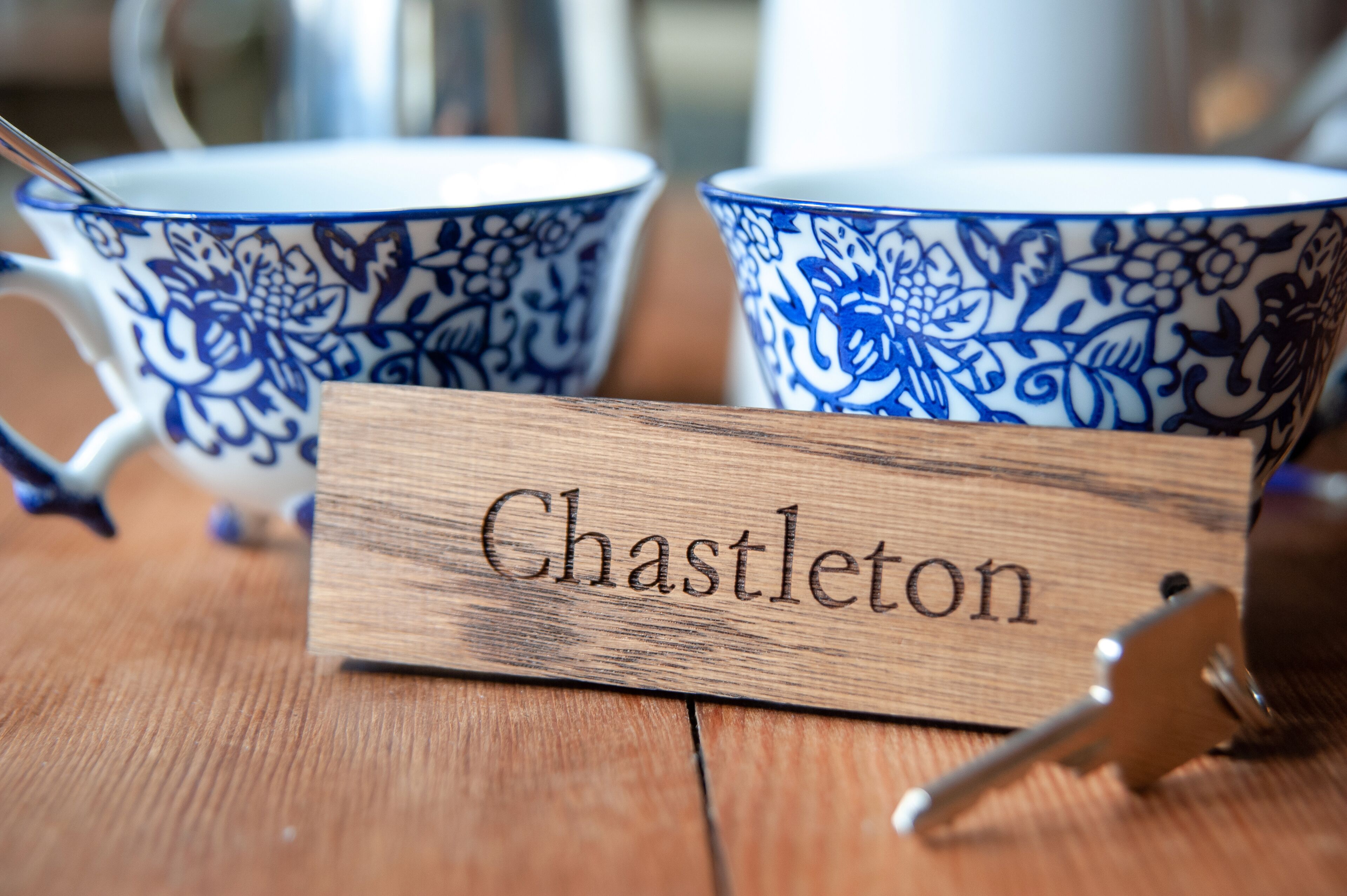 Two blue and white patterned cups on a wooden table with a sign that reads "Chastleton".