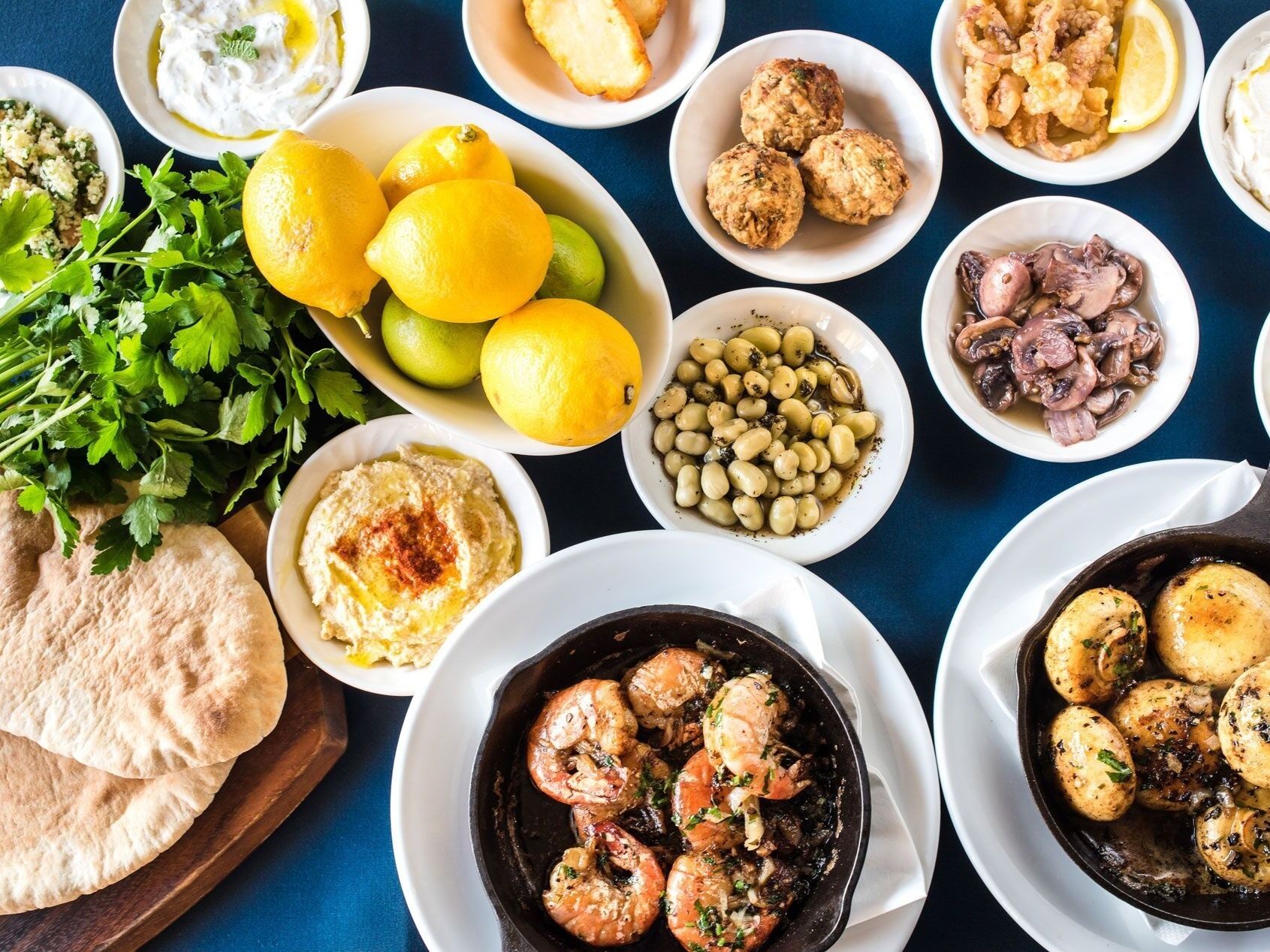 Un assortiment de plats comprenant du houmous, des citrons, des olives et des fruits de mer.