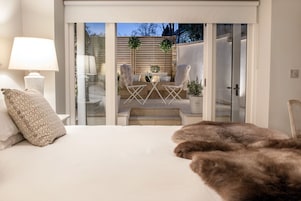 Un dormitorio con cama, lámpara y vistas a un patio exterior con mesa y sillas.