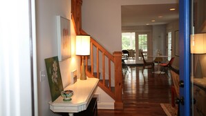A hallway with a wooden staircase, a dining area with chairs and a table, and a door with a blue frame. - Farmhouse (Saugatuck)